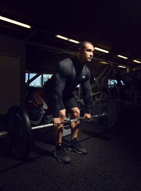 Muscular man lifting heavy barbell in gym during workout, showcasing strength and focus.